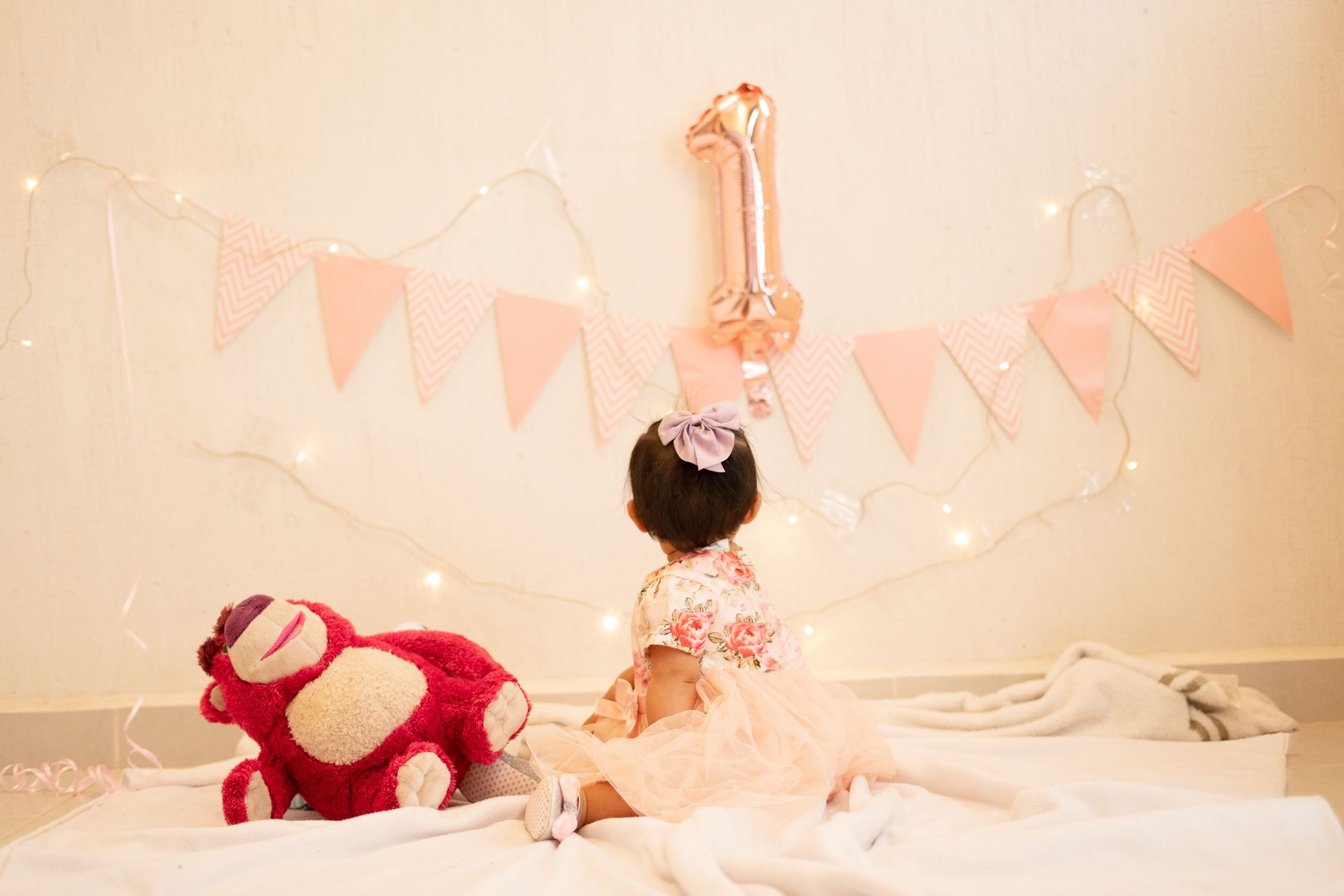 A charming first birthday setup with a baby girl, pink decor, and festive balloons.