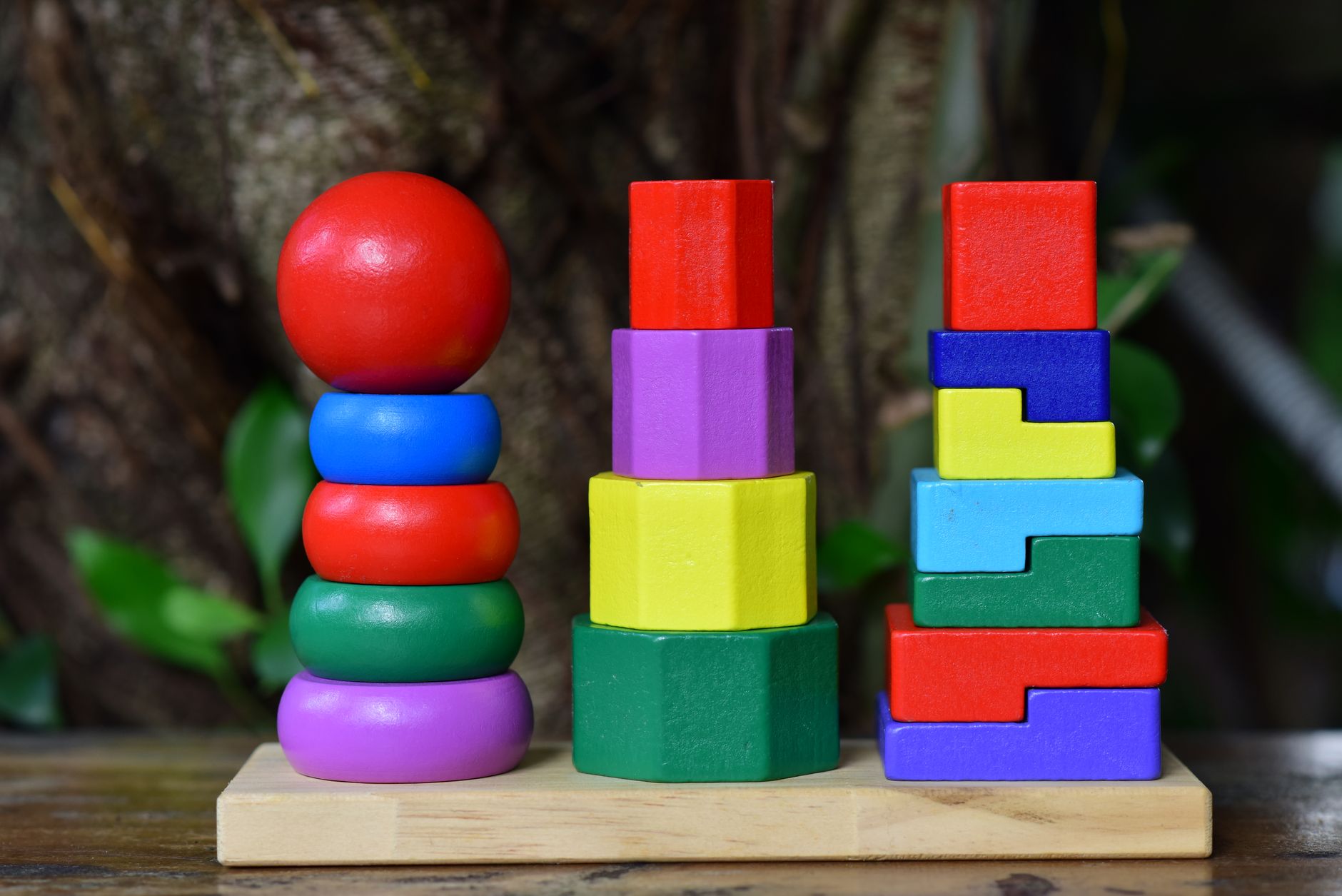 Brightly colored wooden stacking toy set on wooden base, outdoors.