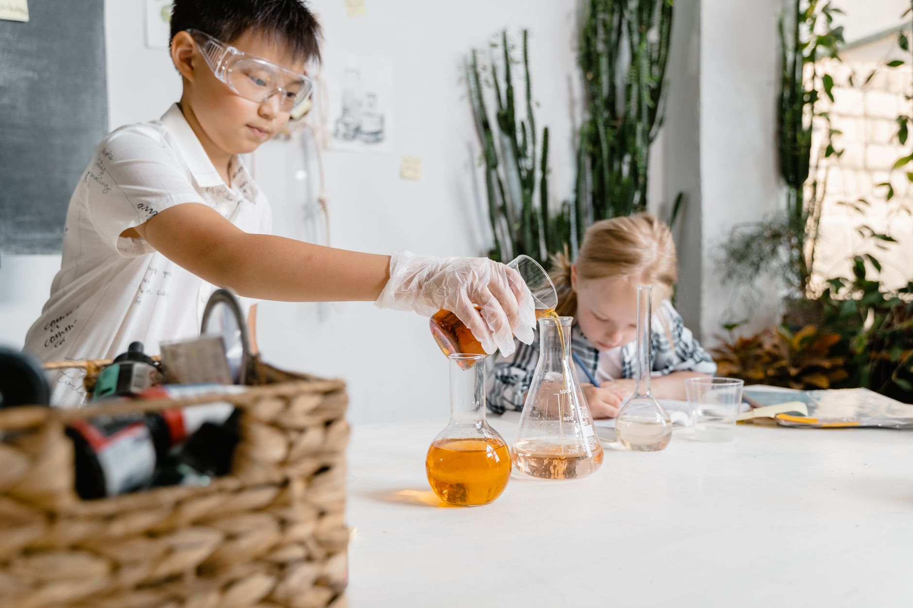 Young students engaged in a science experiment with laboratory glassware indoors.