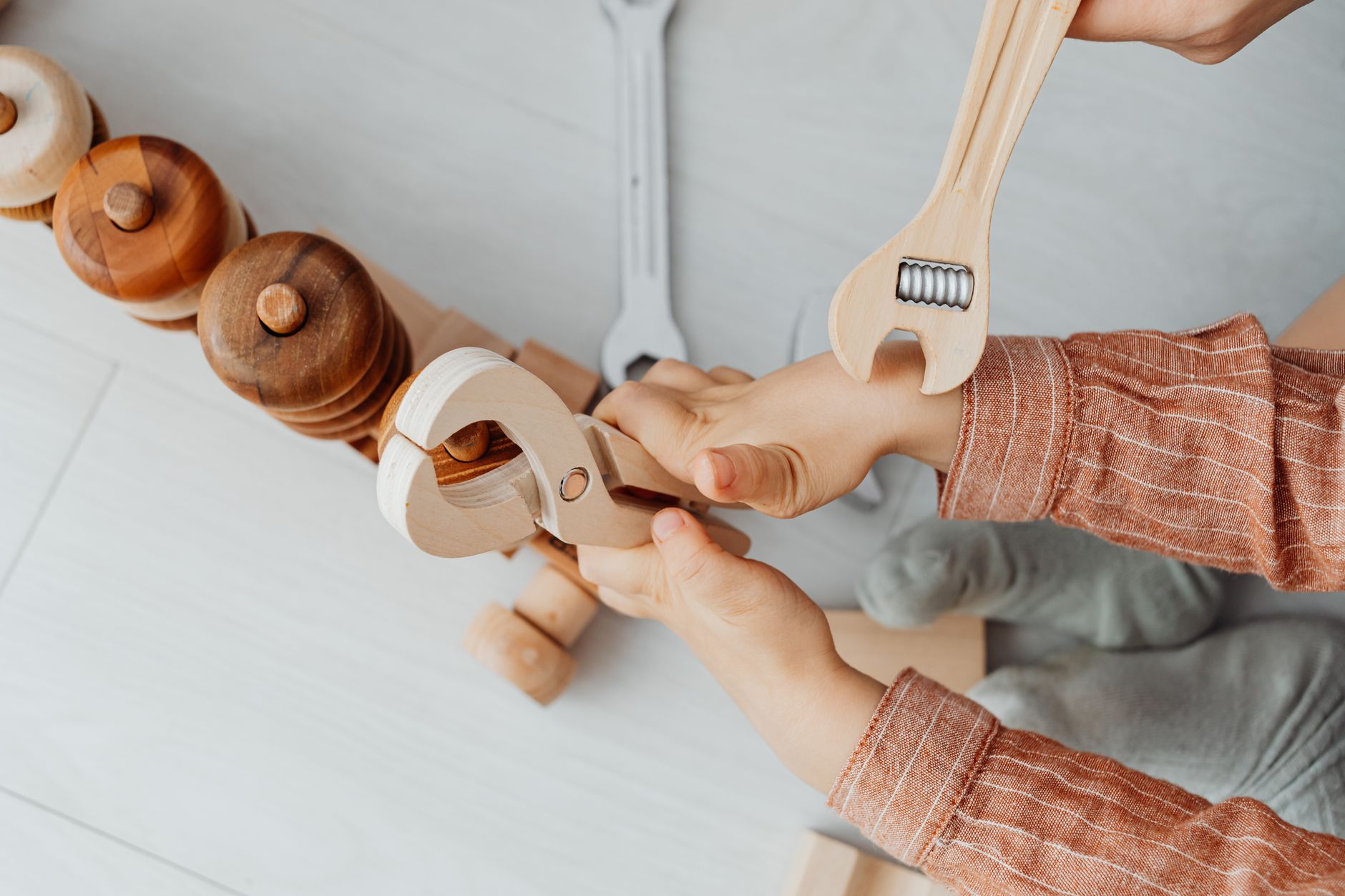 Close-up of a child playing with wooden toy tools, enhancing creativity and motor skills.