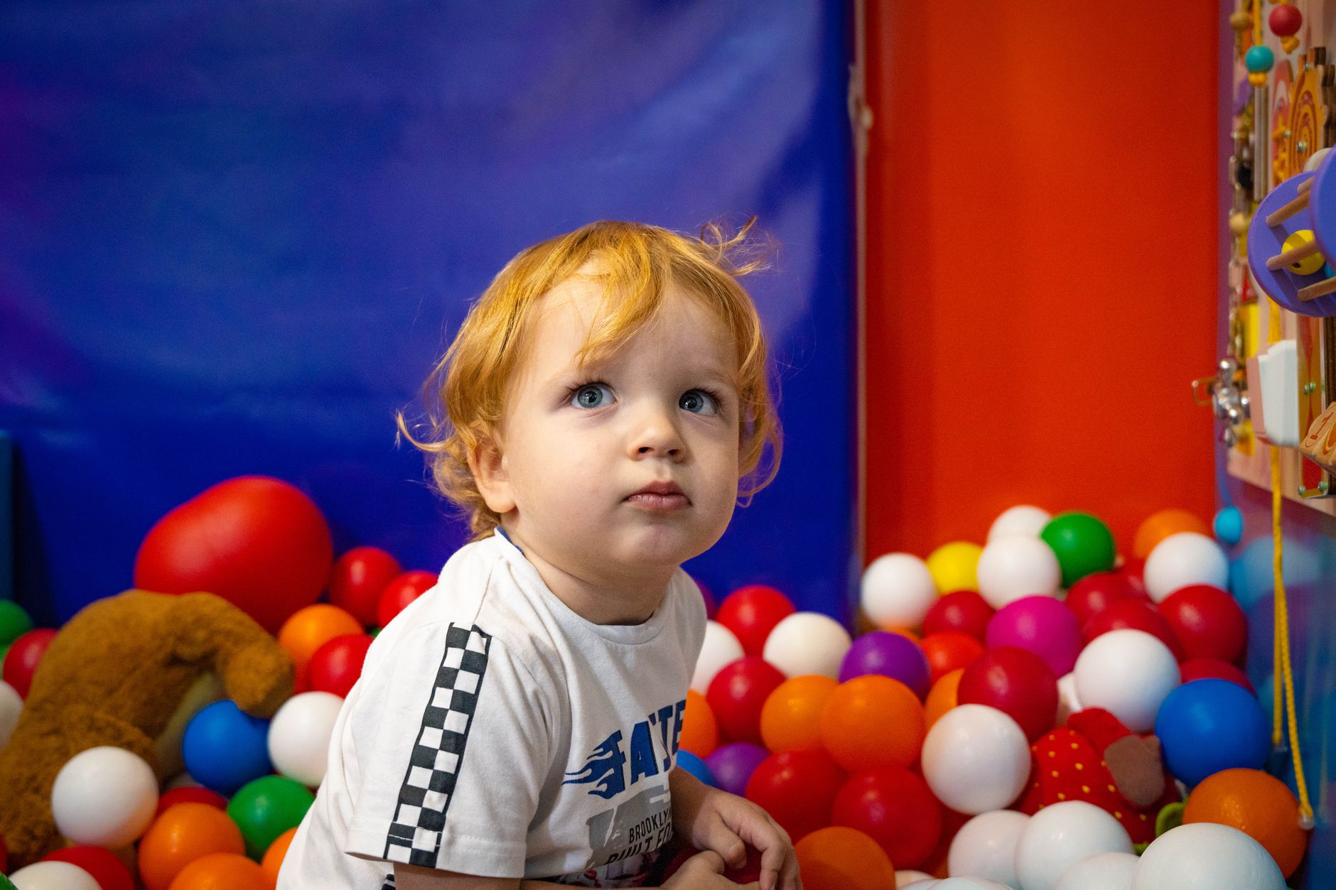 Adorable toddler exploring a vibrant indoor ball pit. Ideal for playful and family-themed content.