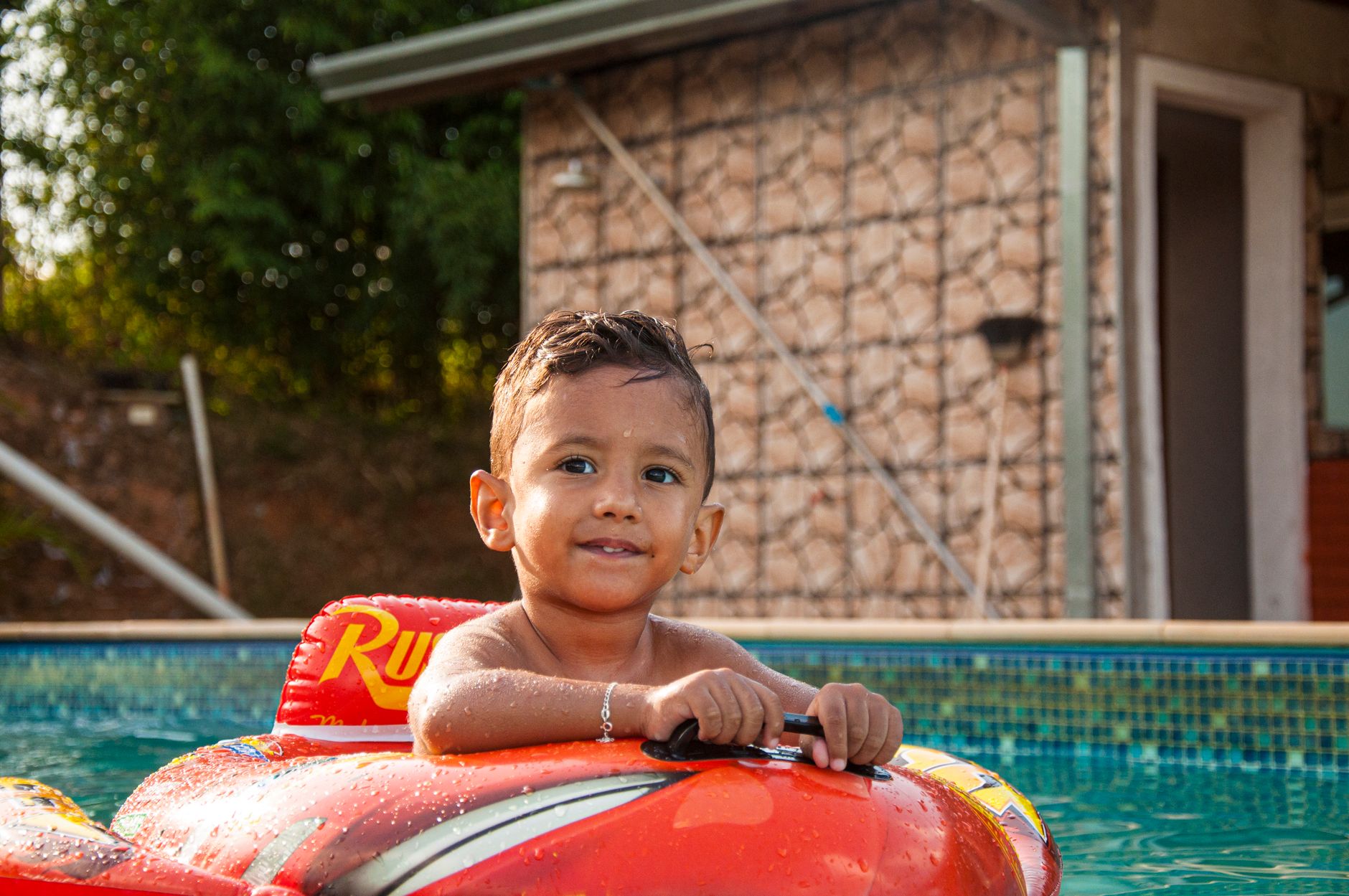 A young boy happily playing in an inflatable ring in a swimming pool on a sunny summer day.