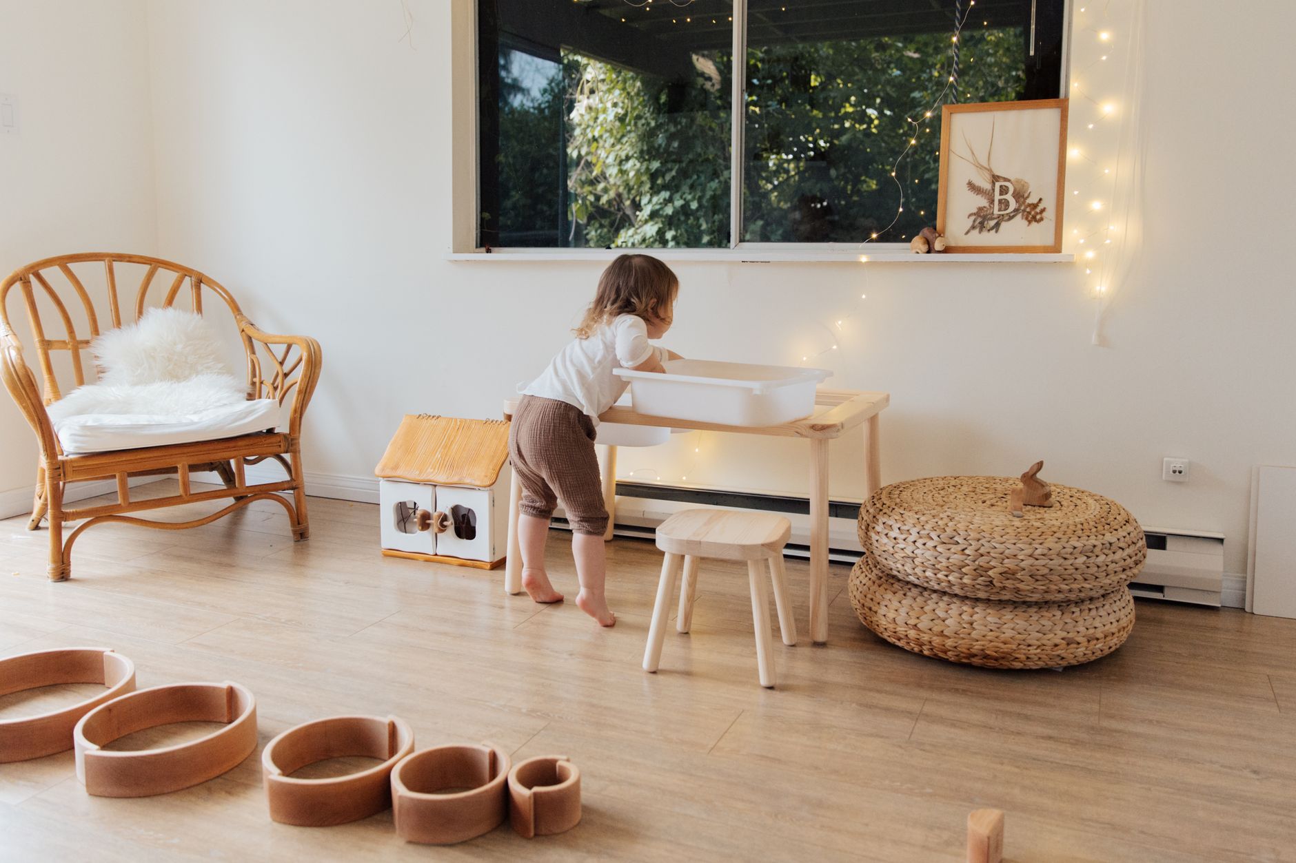Adorable toddler exploring a warm, minimalist living room with wooden decor and soft lighting.