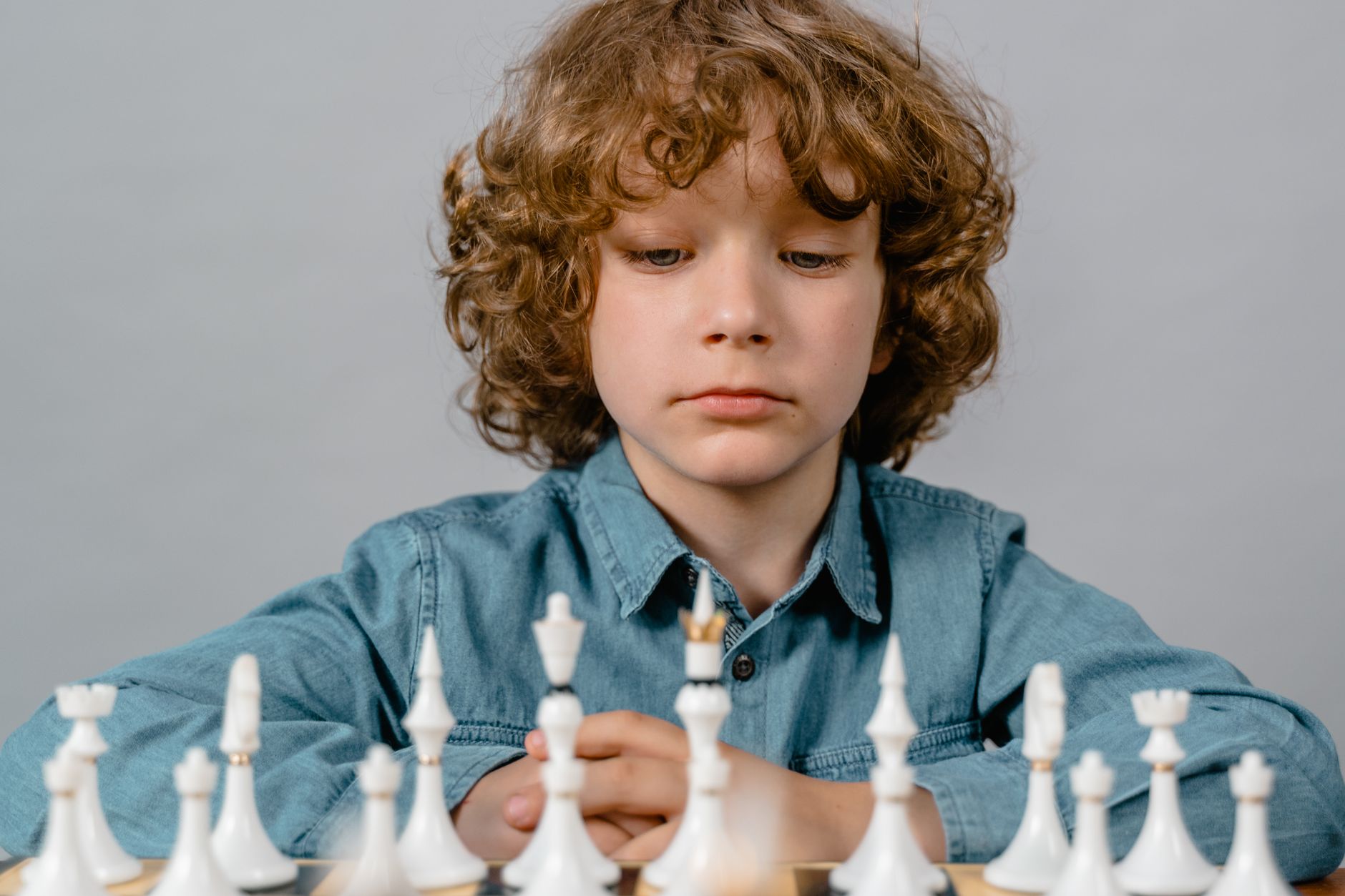 A child deep in thought planning a chess strategy with concentration and determination.